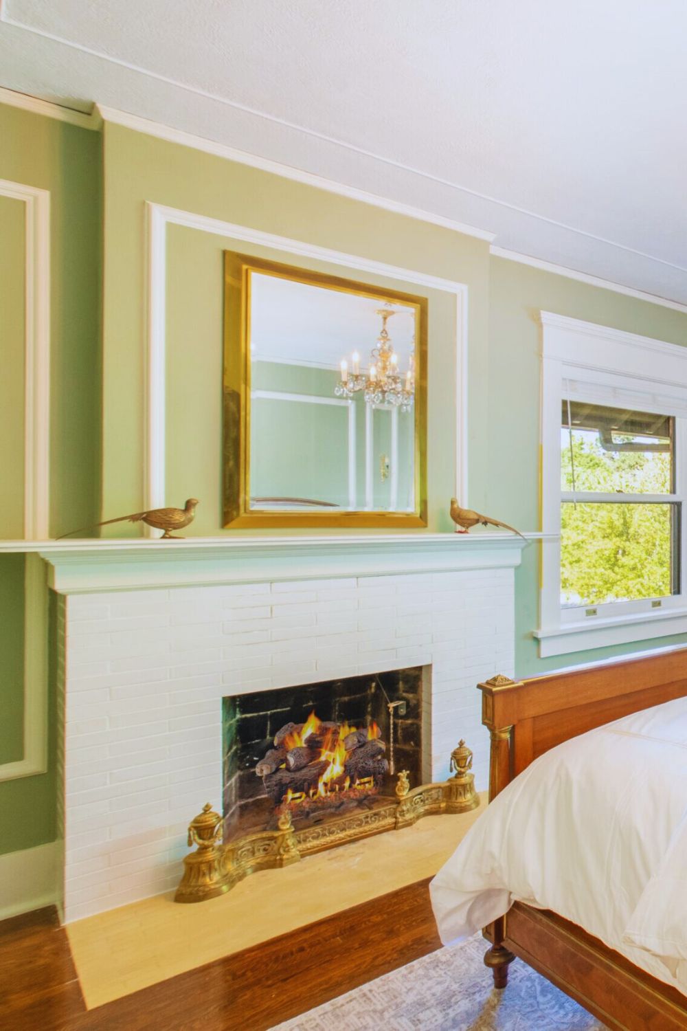 cozy bedroom with white brick fireplace, gold-framed mirror, and green walls at Martha’s Bed and Breakfast in Lincoln, Nebraska