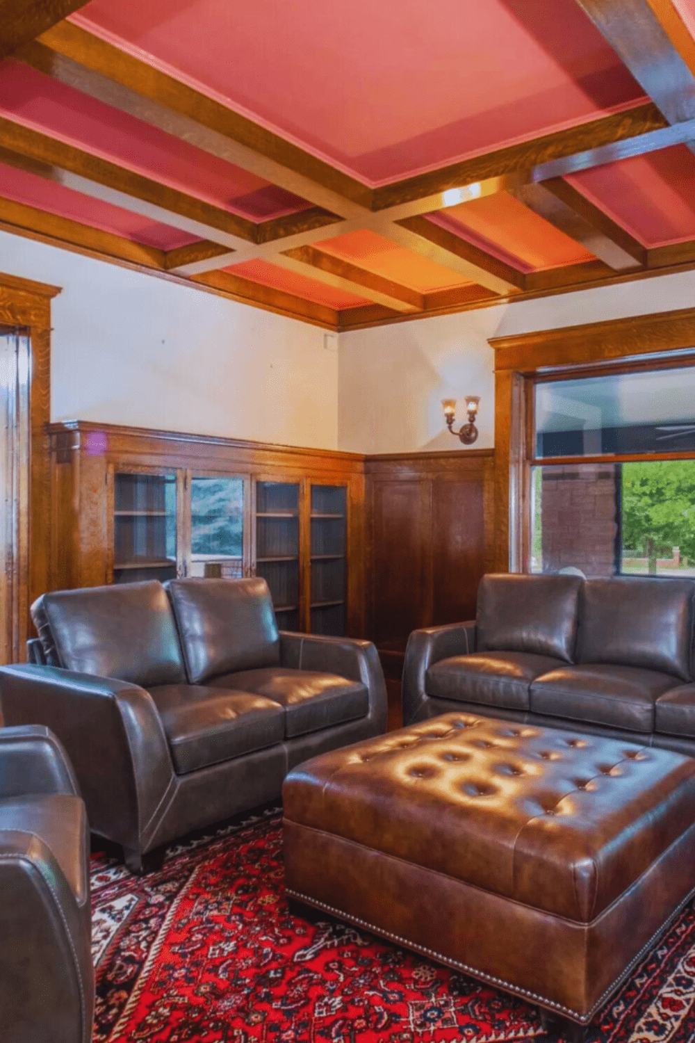 cozy den with leather sofas, large ottoman, and red patterned rug at Martha’s Bed and Breakfast in Lincoln, Nebraska