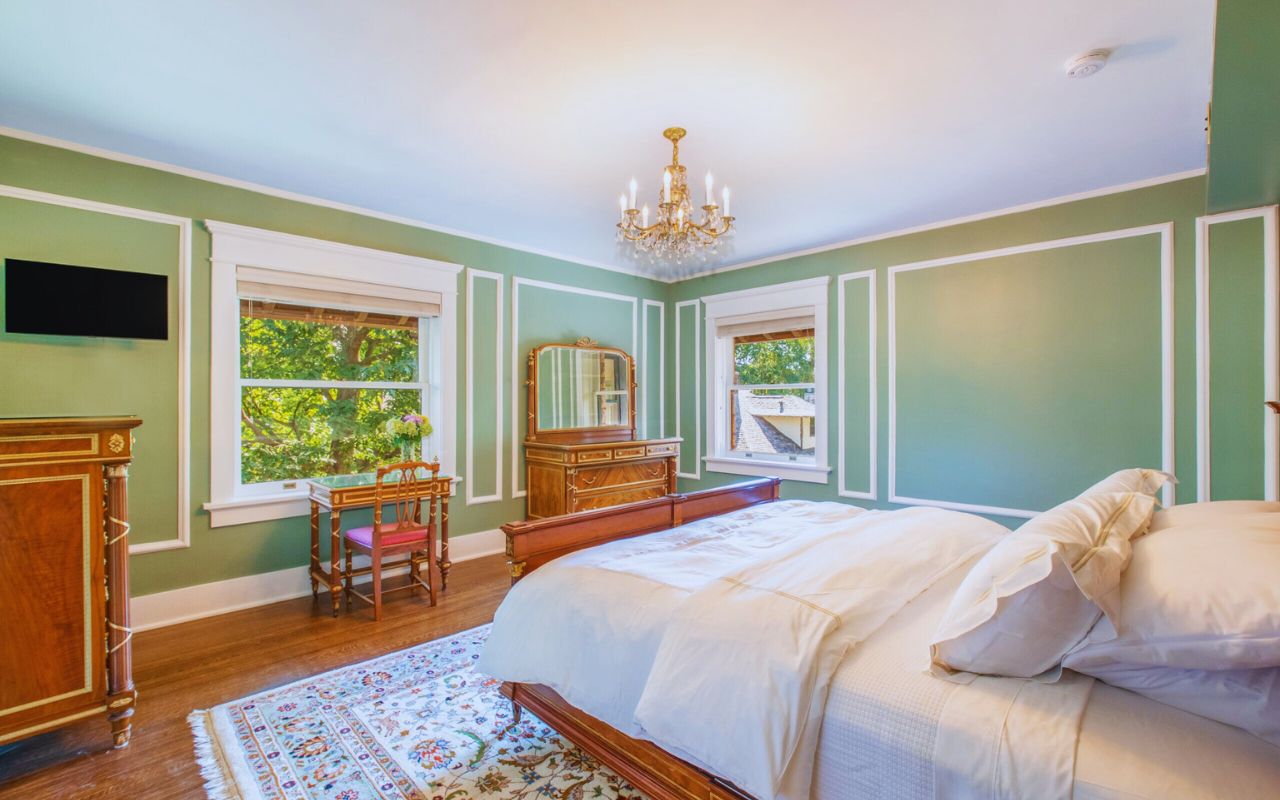 luxury bedroom with carved wooden bed, arched alcove, chandelier, and antique-style decor at Martha’s Bed and Breakfast in Lincoln, Nebraska