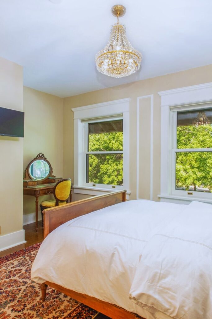 Elegant guest bedroom with vintage chandelier, antique vanity, and garden view at Martha's Bed and Breakfast in Lincoln, Nebraska