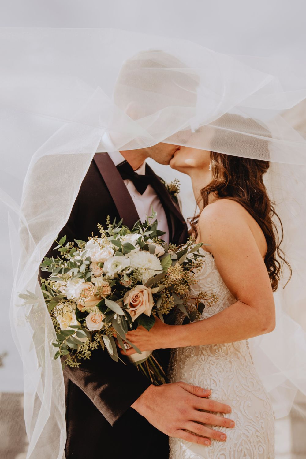 Bride and groom sharing a romantic kiss under a veil with bridal bouquet at Martha's Bed and Breakfast in Lincoln, Nebraska